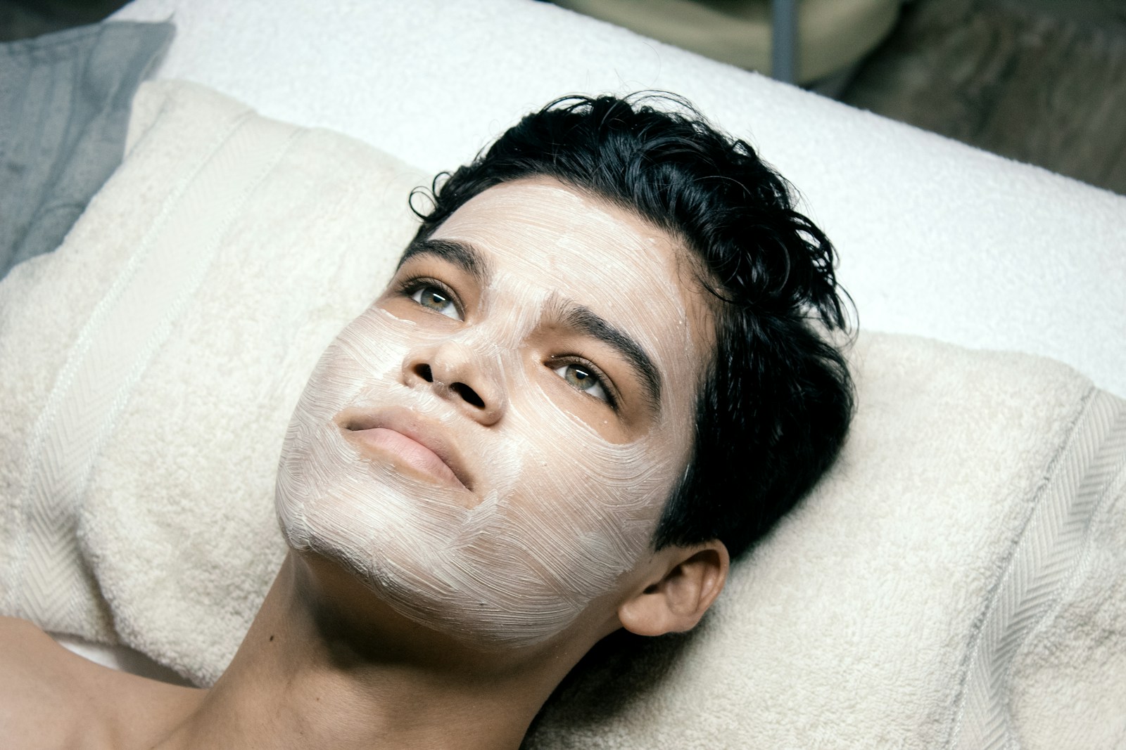 A man laying on a bed with a towel on his head